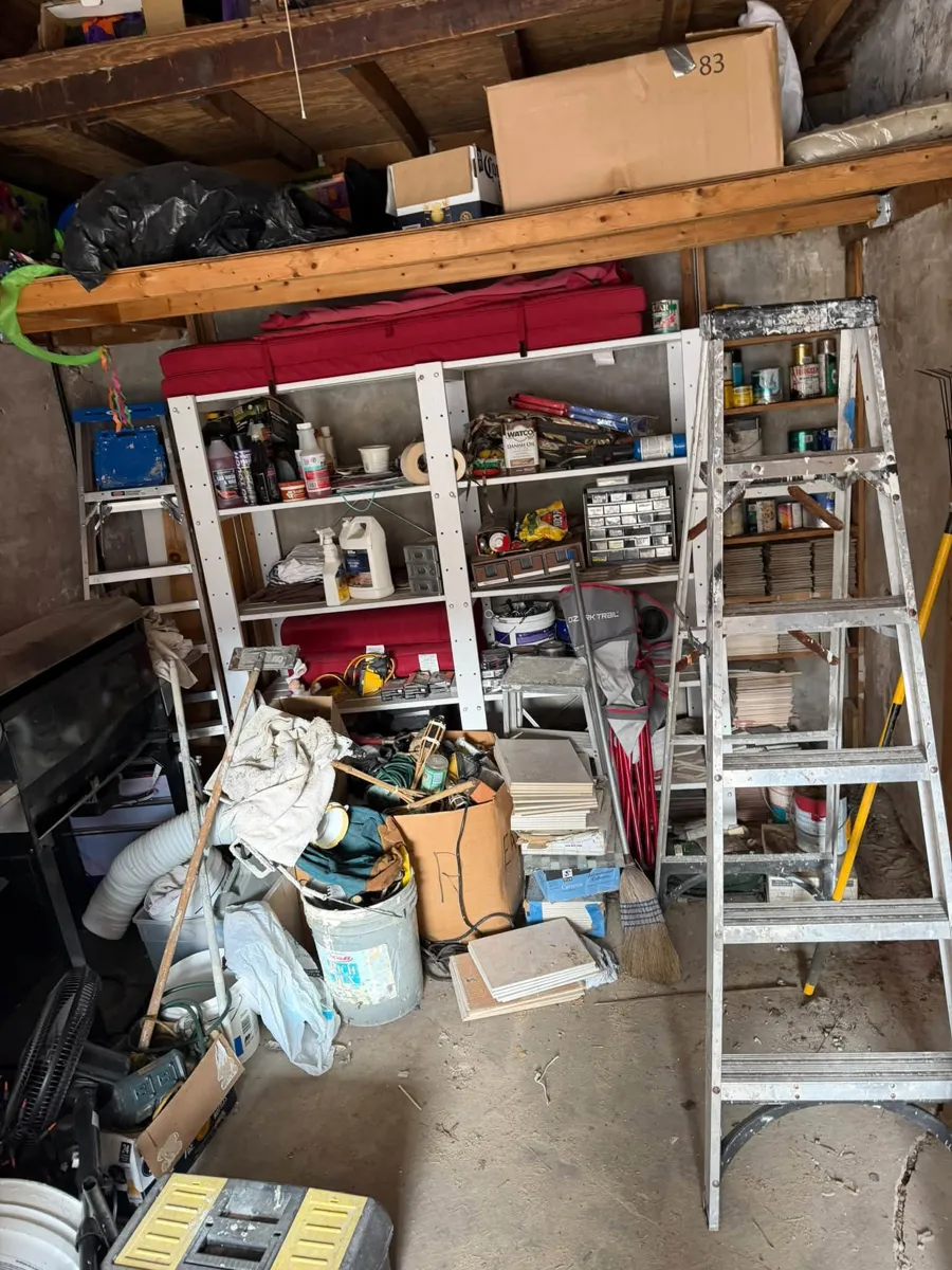 Garage full of shelves, boxes, ladders and junk before the cleanout